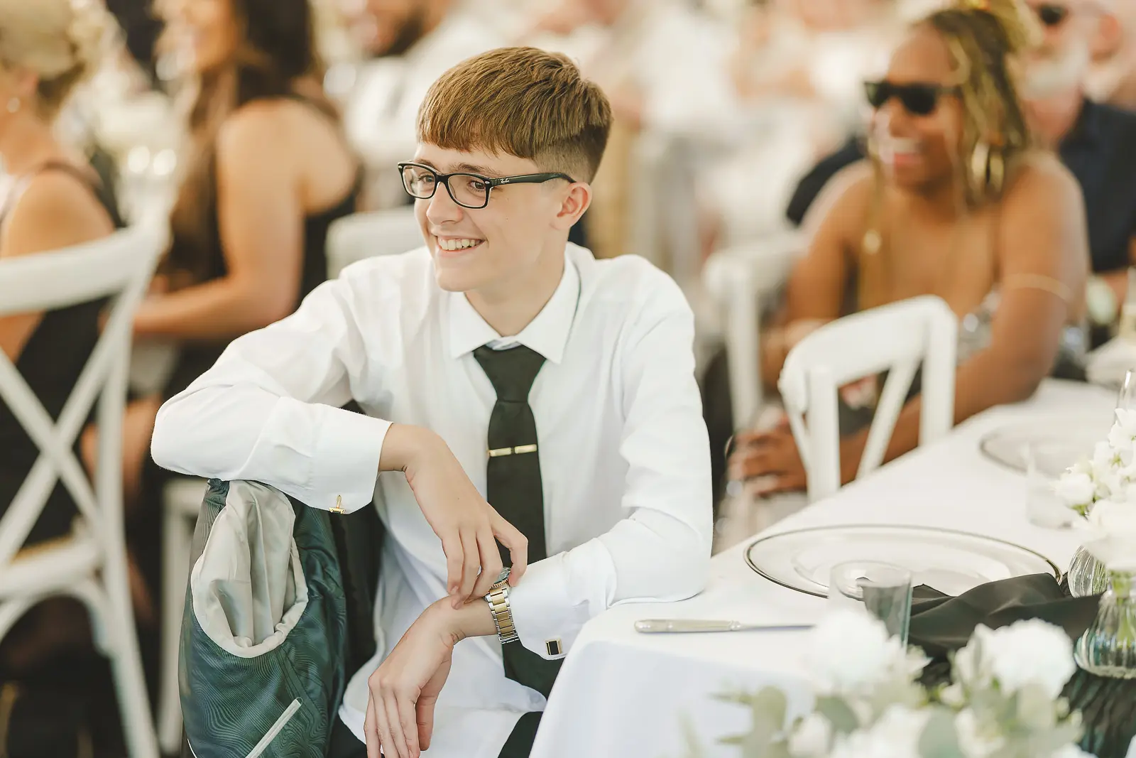 Young guest seated at the marquee during the wedding reception, candid portrait in natural light