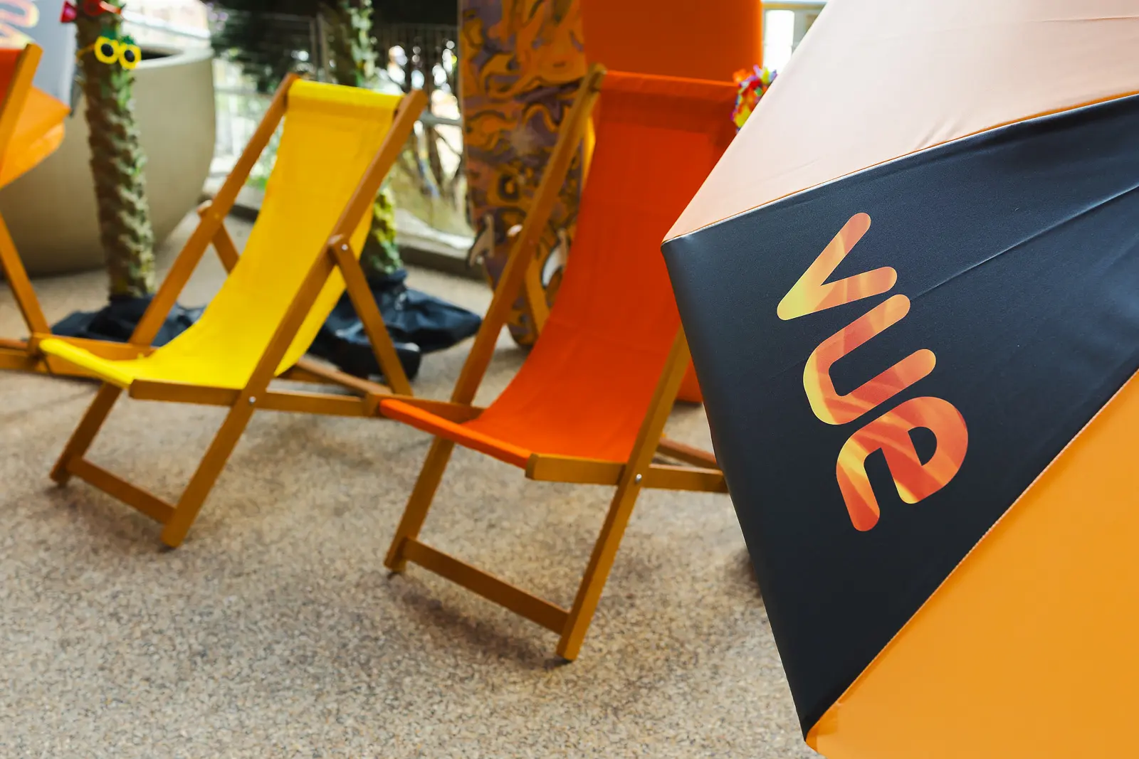 Colourful yellow and orange deckchairs alongside a branded beach parasol as part of an outdoor event setup in Poole