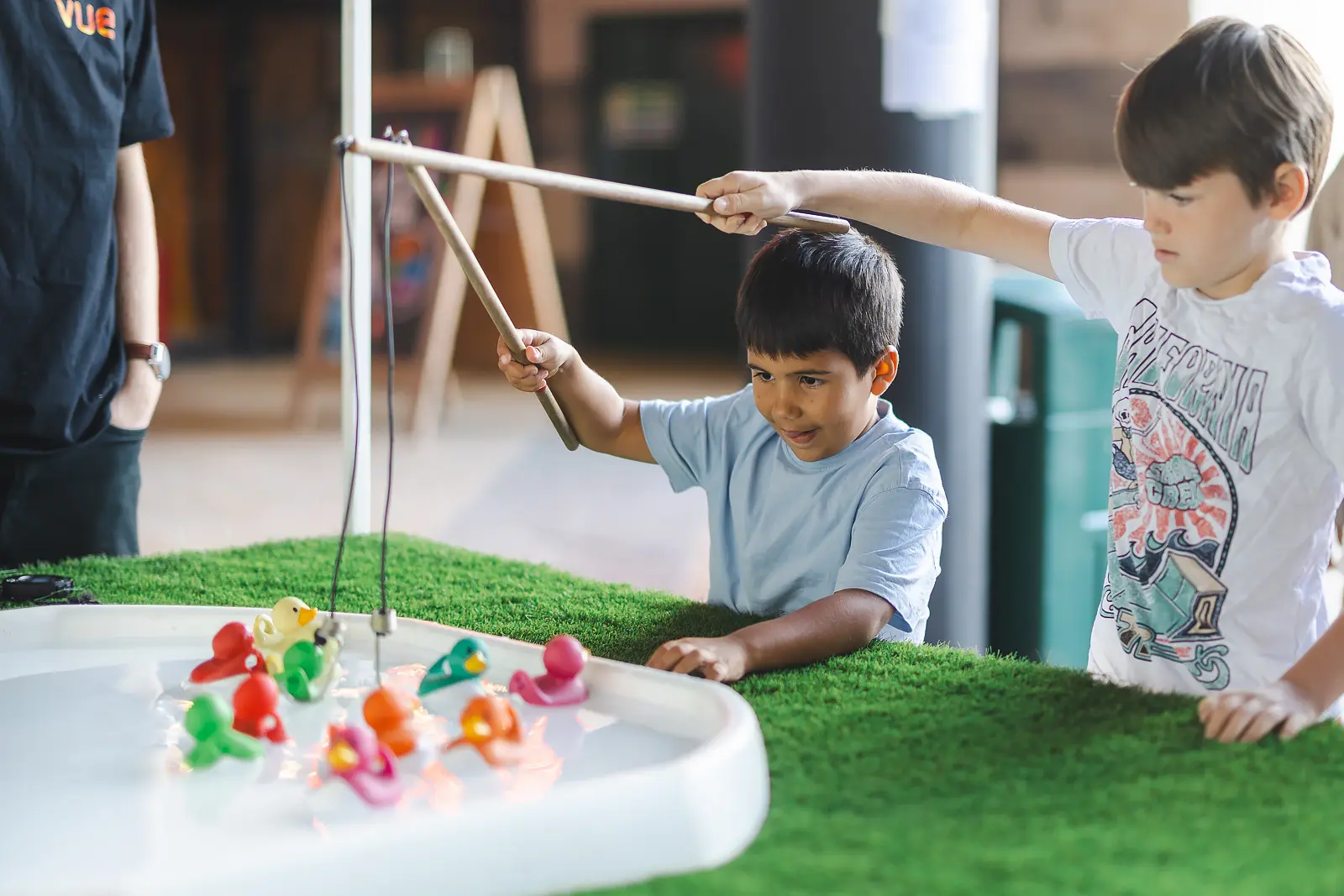 Two boys concentrating on a hook-a-duck fairground game at a family brand event in Poole