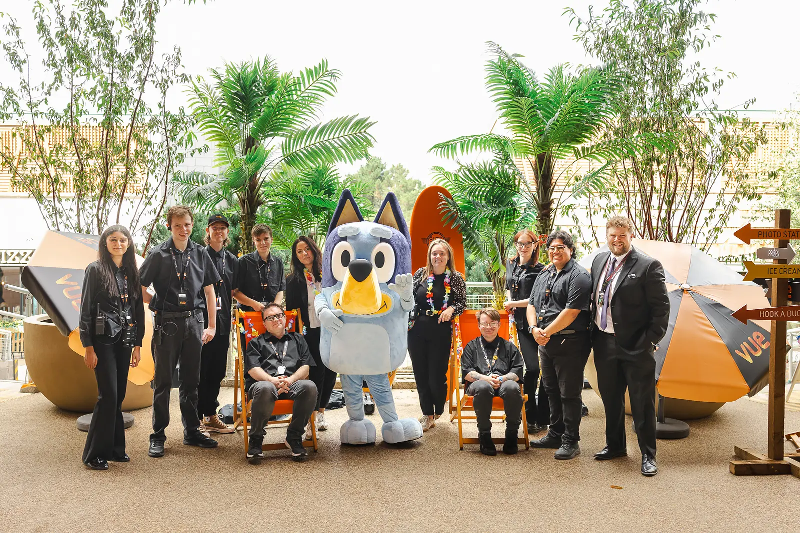 Event staff team posing for a group photograph with a costumed character among beach-themed props at a commercial event in Poole