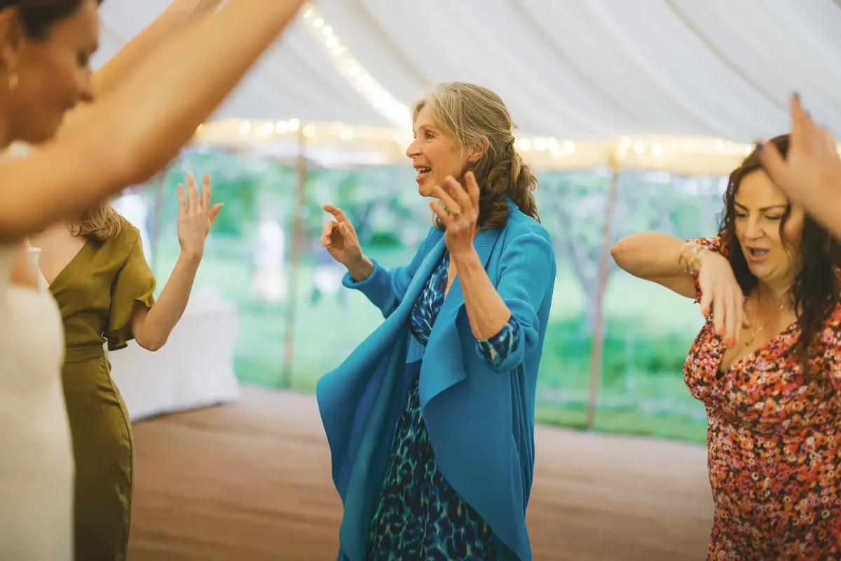 Wedding guests dancing energetically on the floor inside the marquee during the evening reception