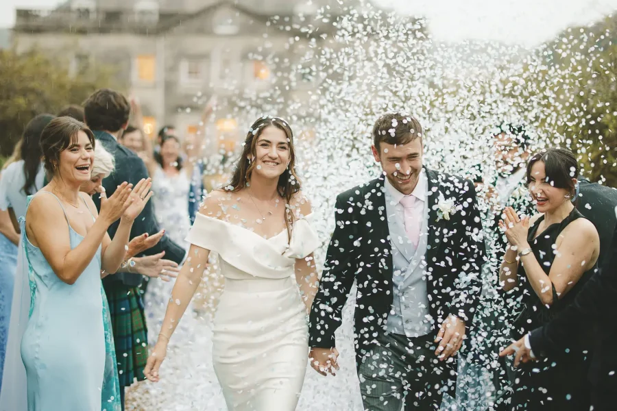 Bride and groom walking through confetti during a rainy wedding in Dorset
