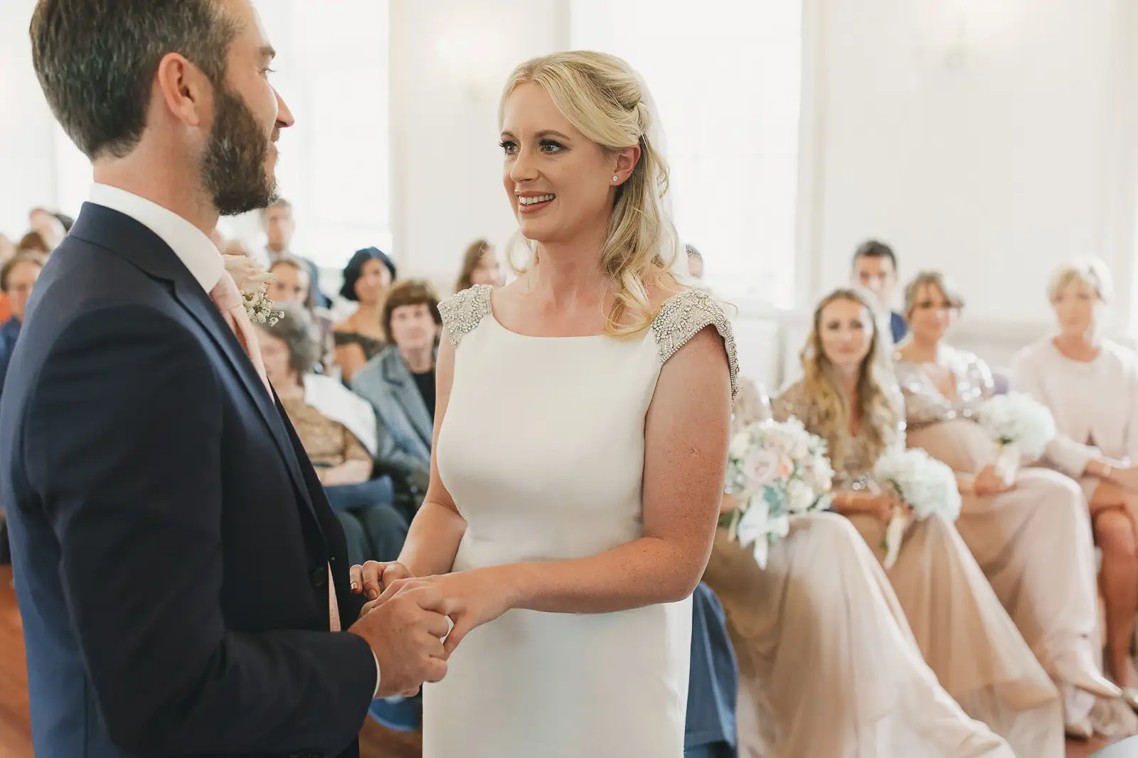 Bride and groom holding hands and exchanging vows during wedding ceremony at Poole Guildhall Registry Office