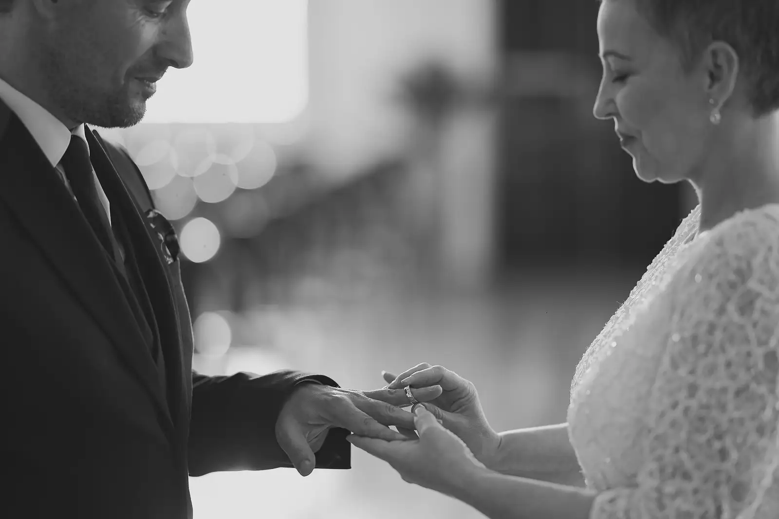 Black and white photograph of bride placing wedding ring on groom's finger during Poole Guildhall registry office ceremony