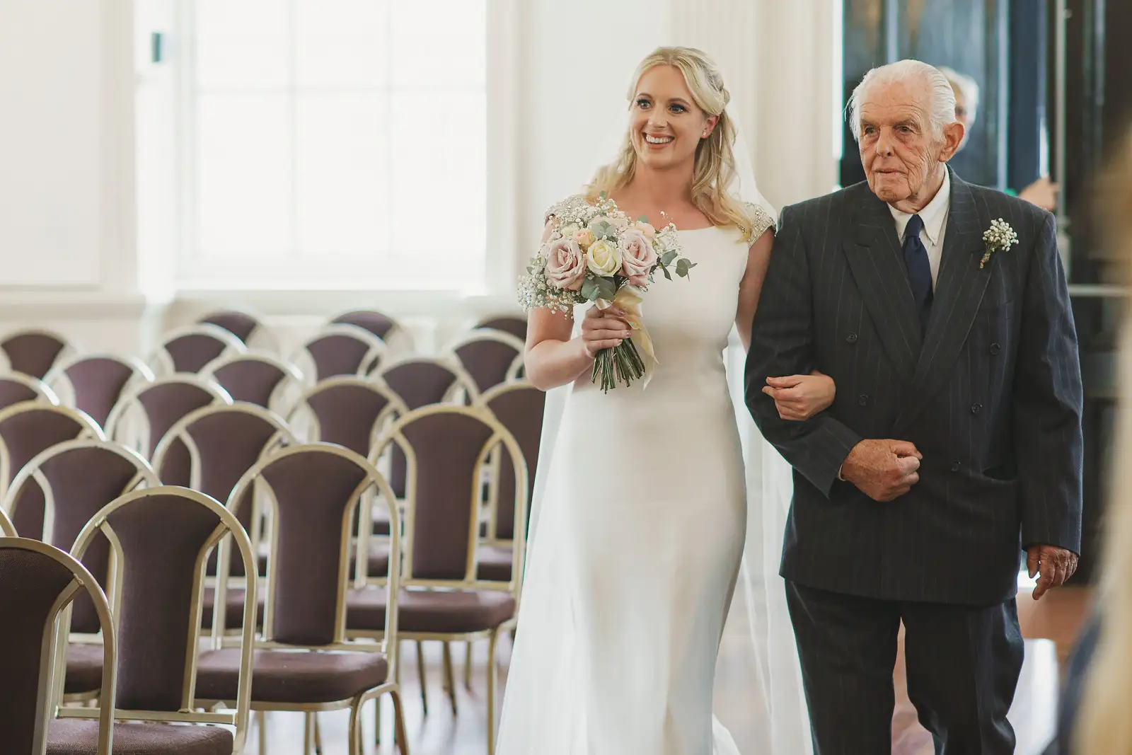 Smiling bride walking down the aisle with her grandfather at Poole Guildhall Registry Office wedding
