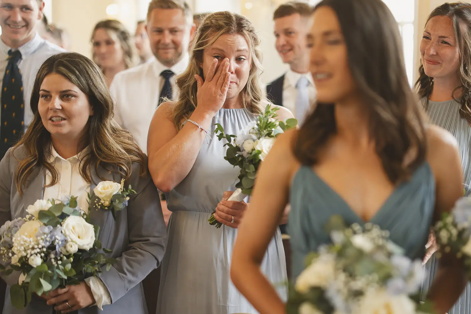 Bridesmaid wiping happy tears during wedding ceremony at Poole Guildhall, surrounded by fellow bridesmaids in blue dresses