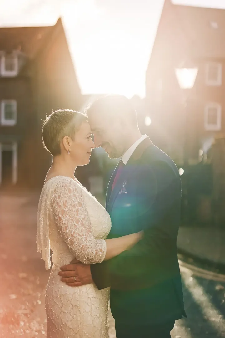 Bride and groom nose to nose in stunning golden backlight on a Poole Old Town street, warm sun flare glowing behind them