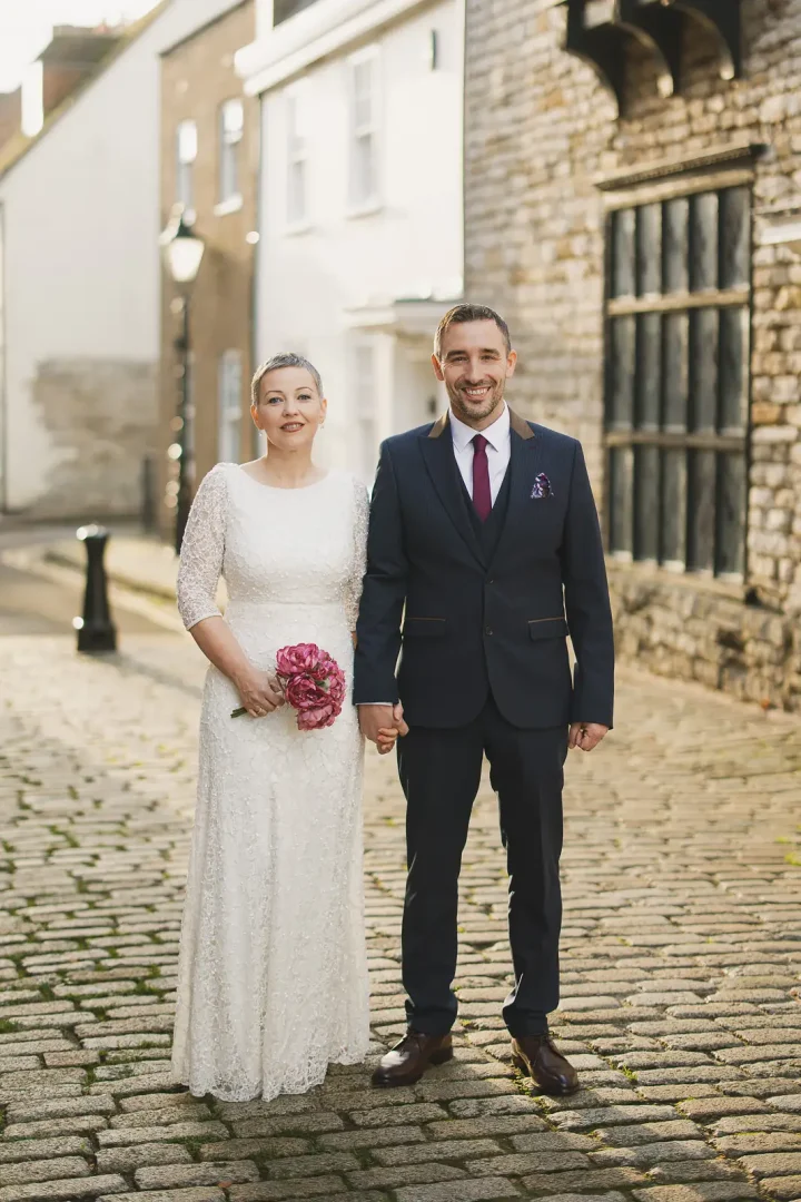 Bride and groom standing together on a historic cobbled street in Poole Old Town after their registry office wedding