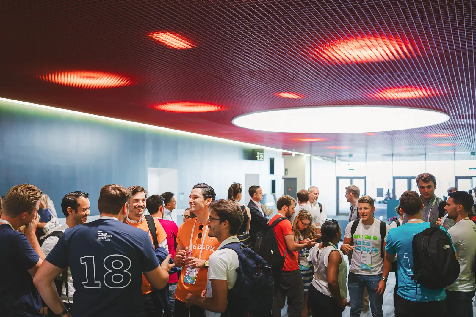 Large group of conference delegates networking in the ExCeL London venue foyer with dramatic circular ceiling lights