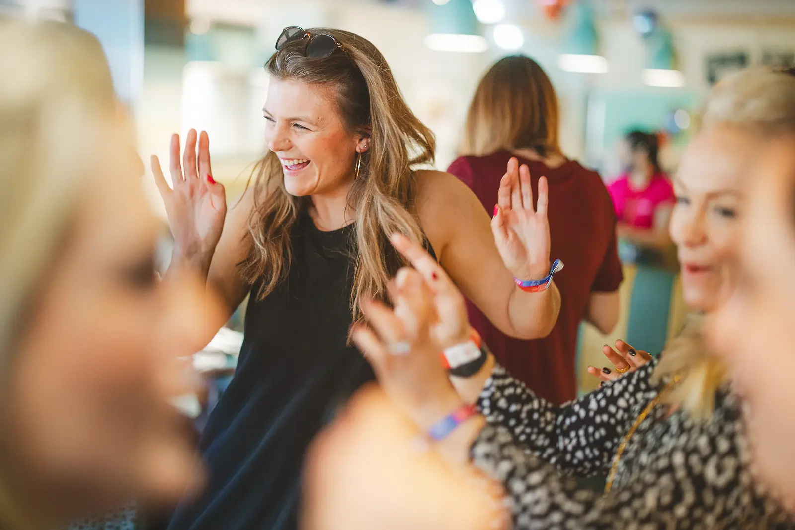 Women laughing and raising hands at a lively group event captured in documentary style