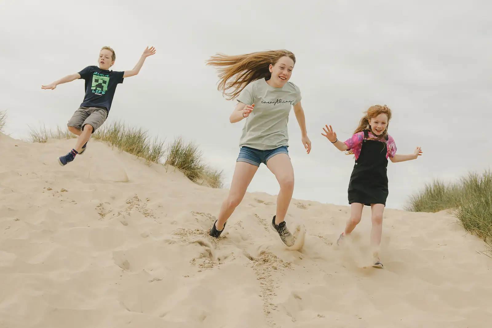 Children playing in the sand dunes during a documentary family photography shoot near Sandbanks.