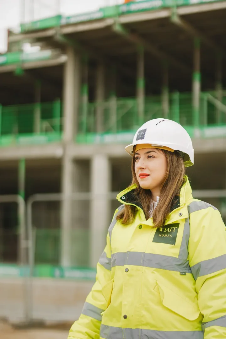 Female staff member in hi-vis jacket and hard hat photographed on location at an active residential development site in Dorset