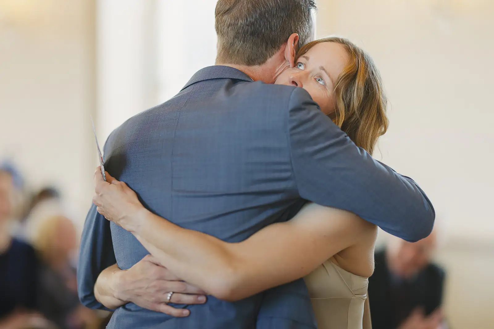 Bride and groom sharing an emotional embrace after their wedding ceremony at Poole Guildhall, bride's joyful face over his shoulder