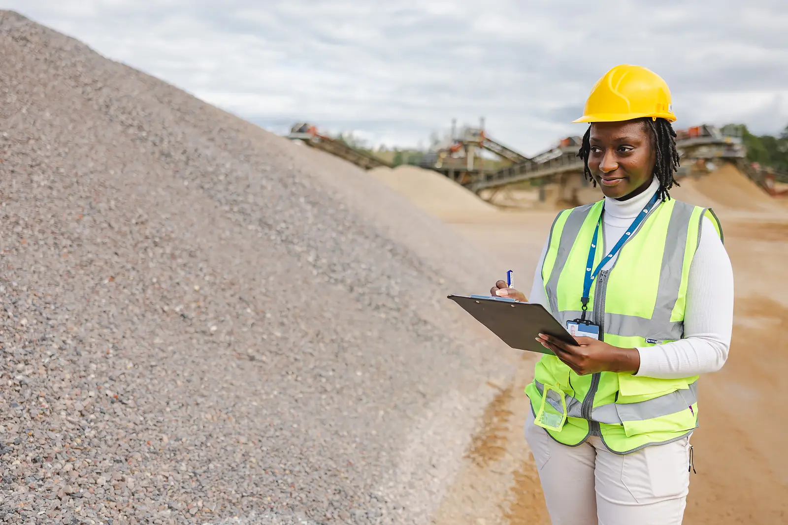 Monitoring and enforcement officer in hi-vis vest and hard hat with clipboard at Woodsford Quarry, Dorset
