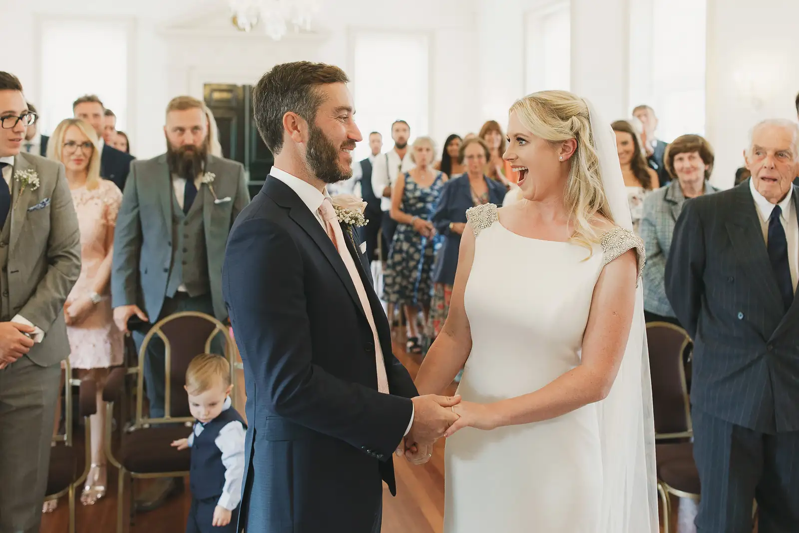 Bride and groom laughing during their wedding ceremony at Poole Guildhall with guests watching