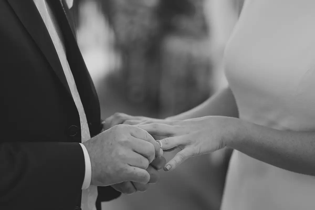 Close-up black and white photograph of the groom placing a wedding ring on the bride's finger during a Poole Guildhall ceremony.