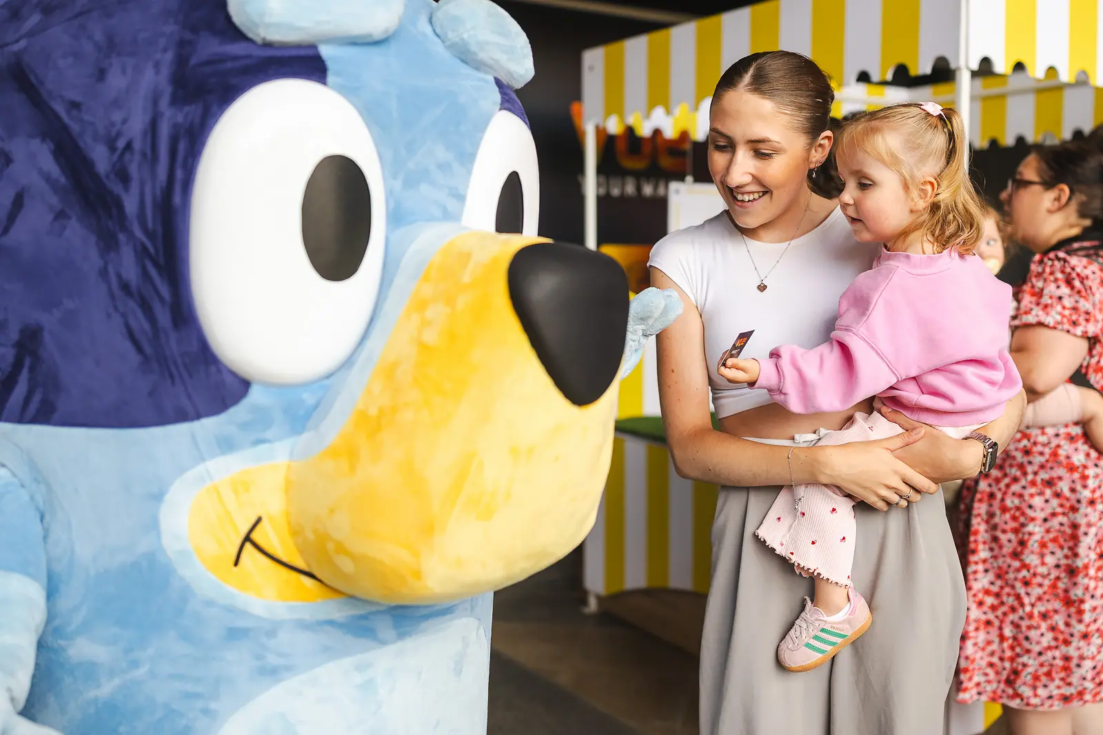Mother and young child engaging with brand mascot character at promotional event in Poole, Dorset