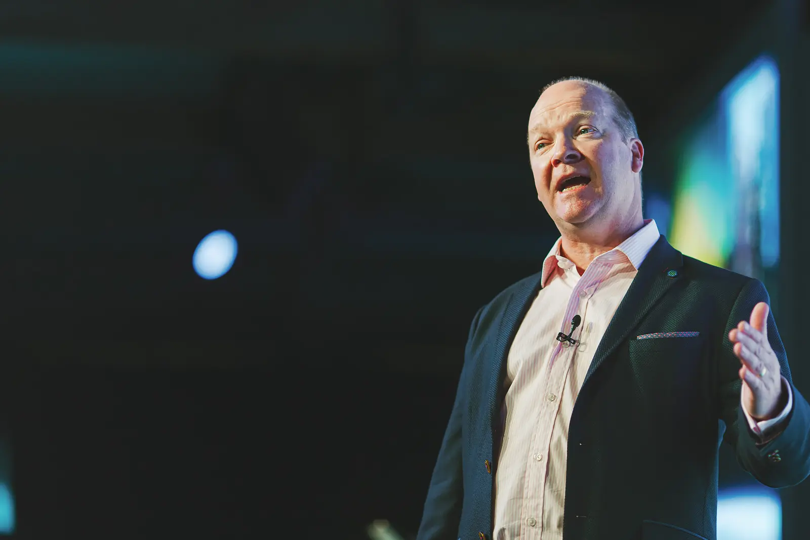Close-up portrait of conference speaker with lapel mic presenting on stage at Tobacco Dock London event