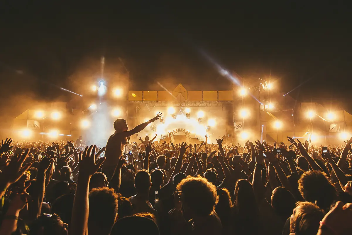 Crowd with raised hands in front of a brightly lit main stage at a UK dance music festival, documenting large-scale club culture and festival atmosphere