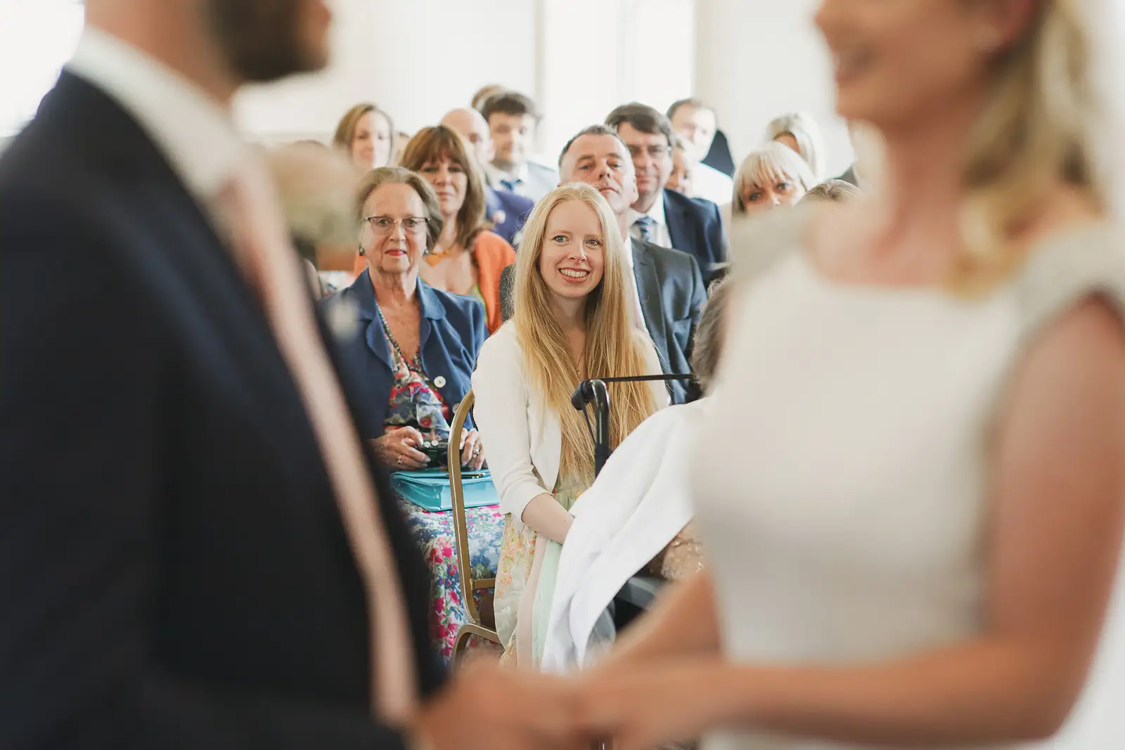 Wedding guests watching ceremony from the couple's perspective inside Poole Guildhall, smiling faces in the crowd