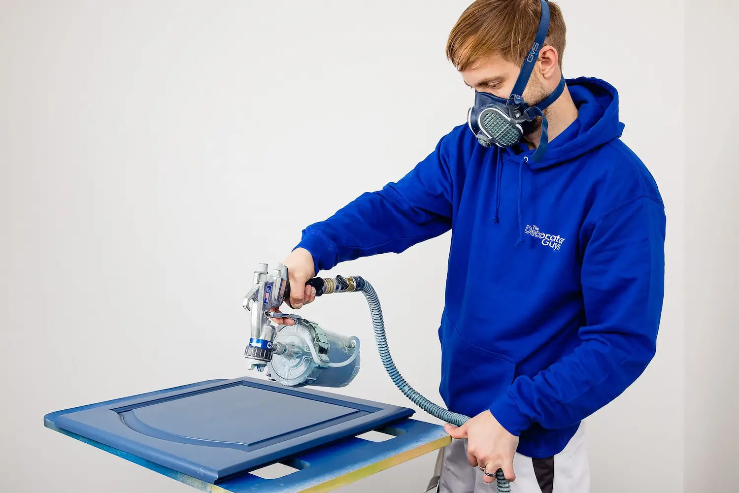 Decorator spraying a cabinet door during a branding photography shoot for a Bournemouth trades business.