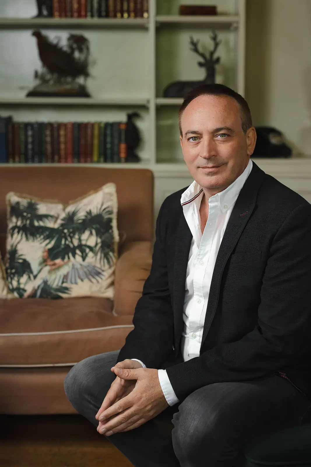 Relaxed business portrait of a man in a navy blazer and open collar shirt at his Bournemouth home