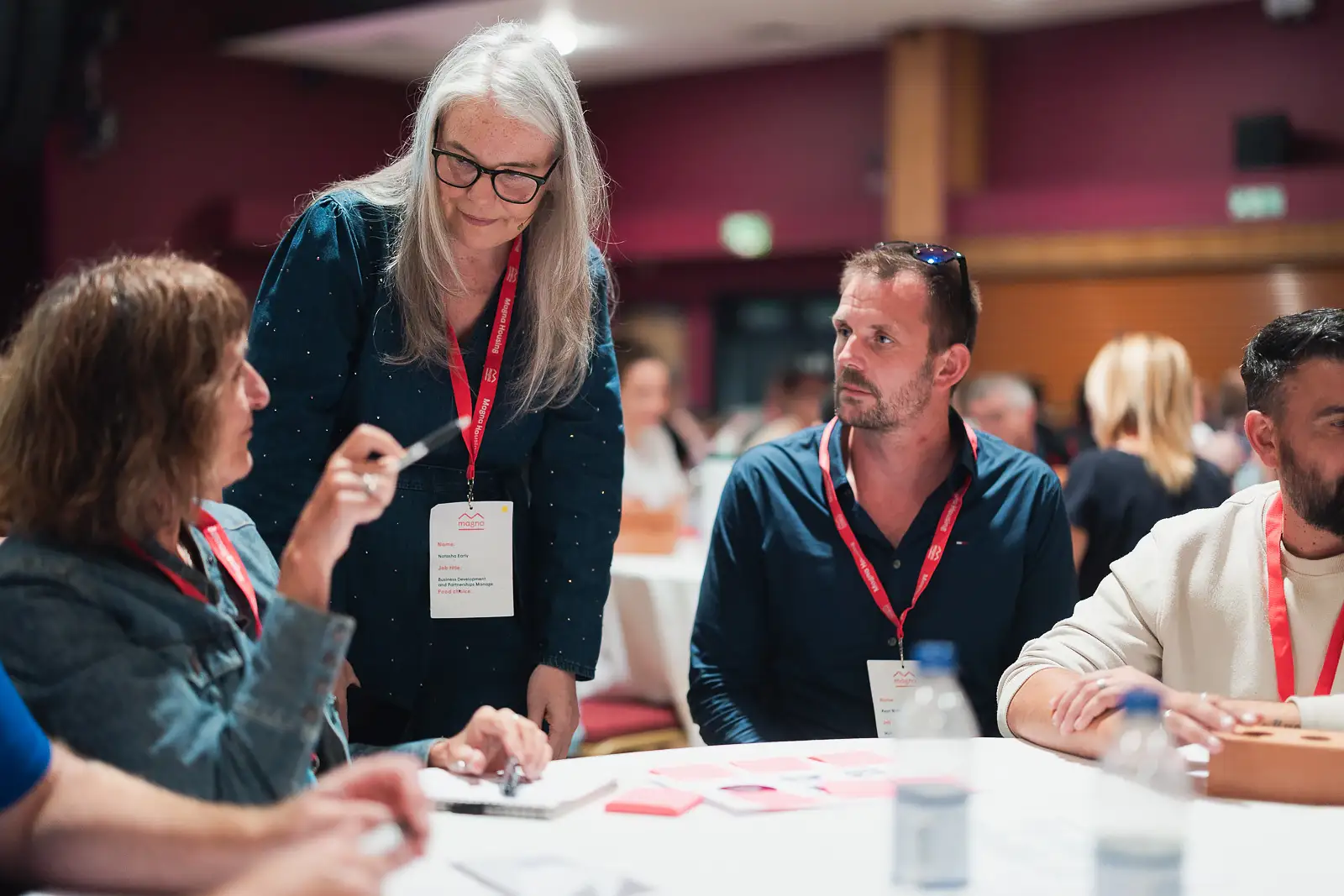 Colleague standing and leading a discussion with teammates around a table during a corporate event in Somerset