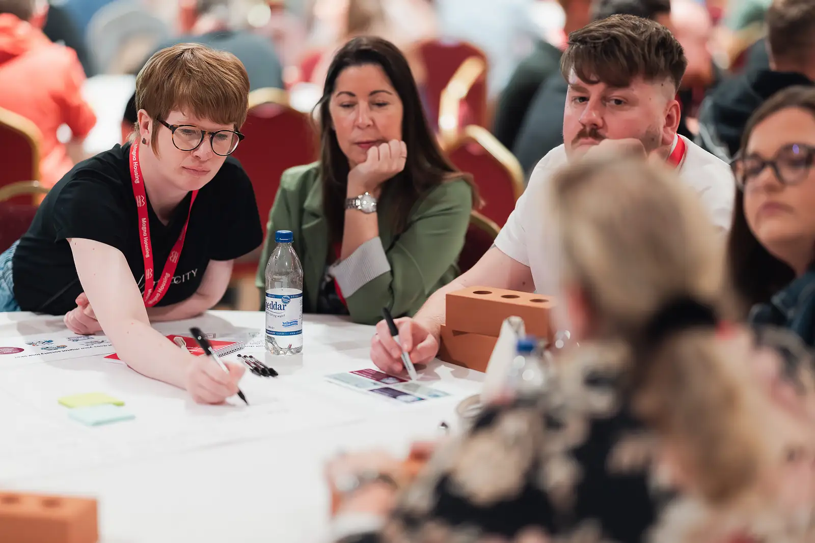 Colleagues focused and writing notes during a workshop task at a corporate conference in Somerset