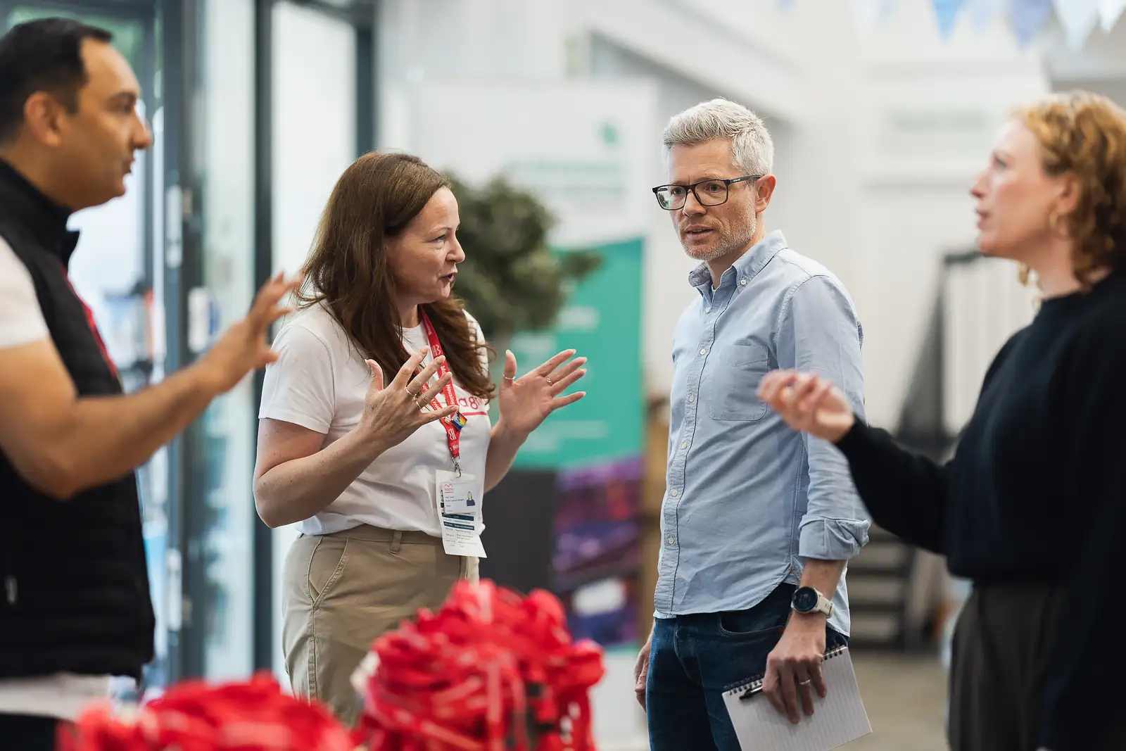 Four colleagues in animated conversation during arrival and networking at a corporate away day at Westlands Theatre