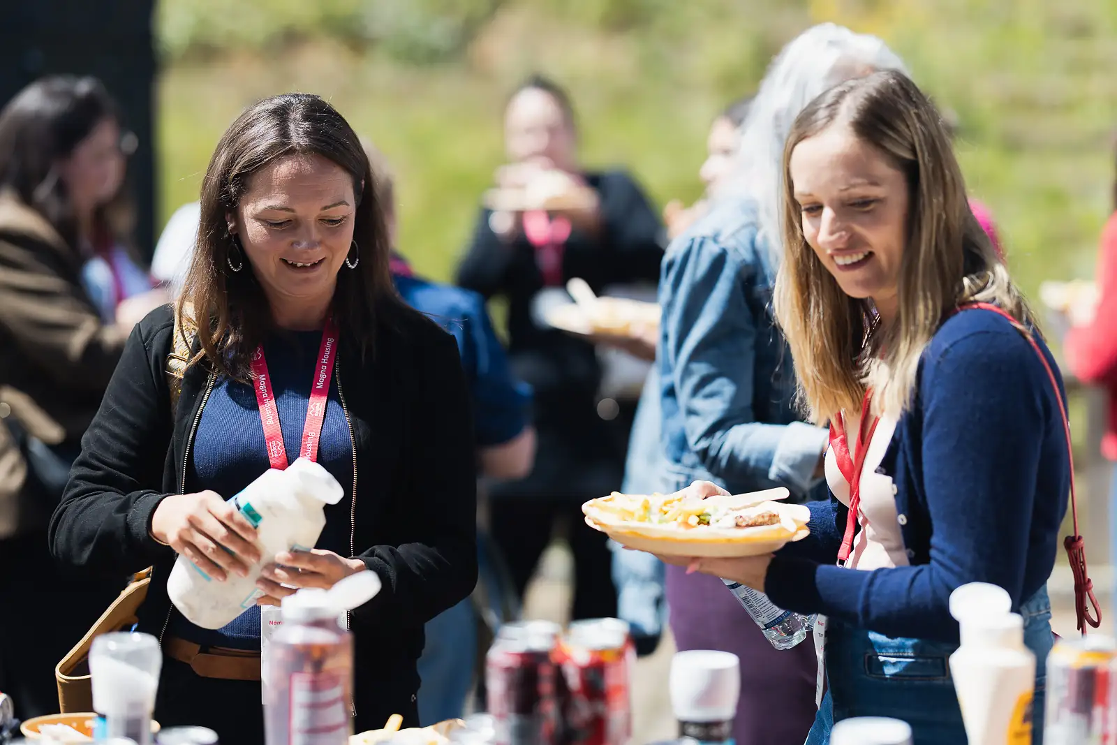 Two colleagues with food and drinks during an outdoor lunch break at a corporate away day in Somerset