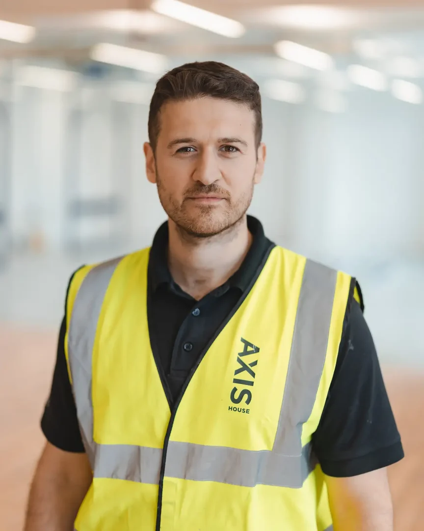 Site manager portrait, direct gaze to camera, glass partitions soft-focused behind — commercial photographer Bournemouth