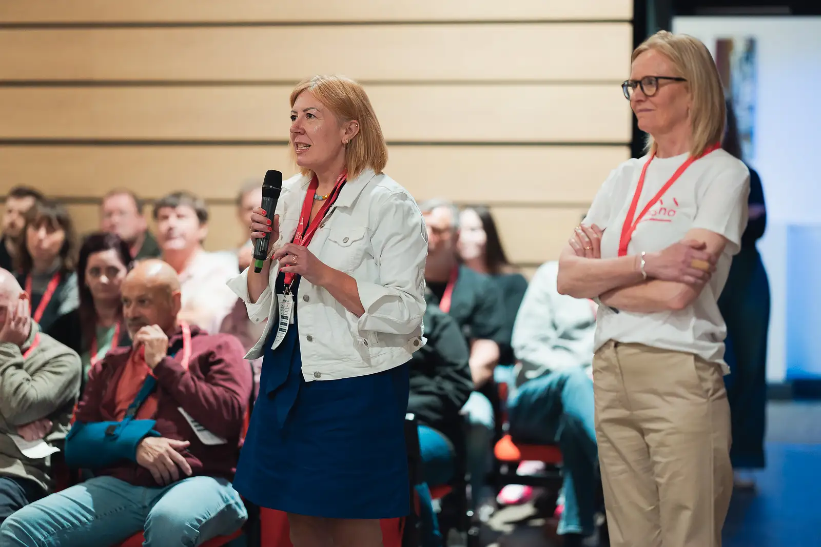 Delegate standing with microphone asking a question during an audience participation session at a corporate conference