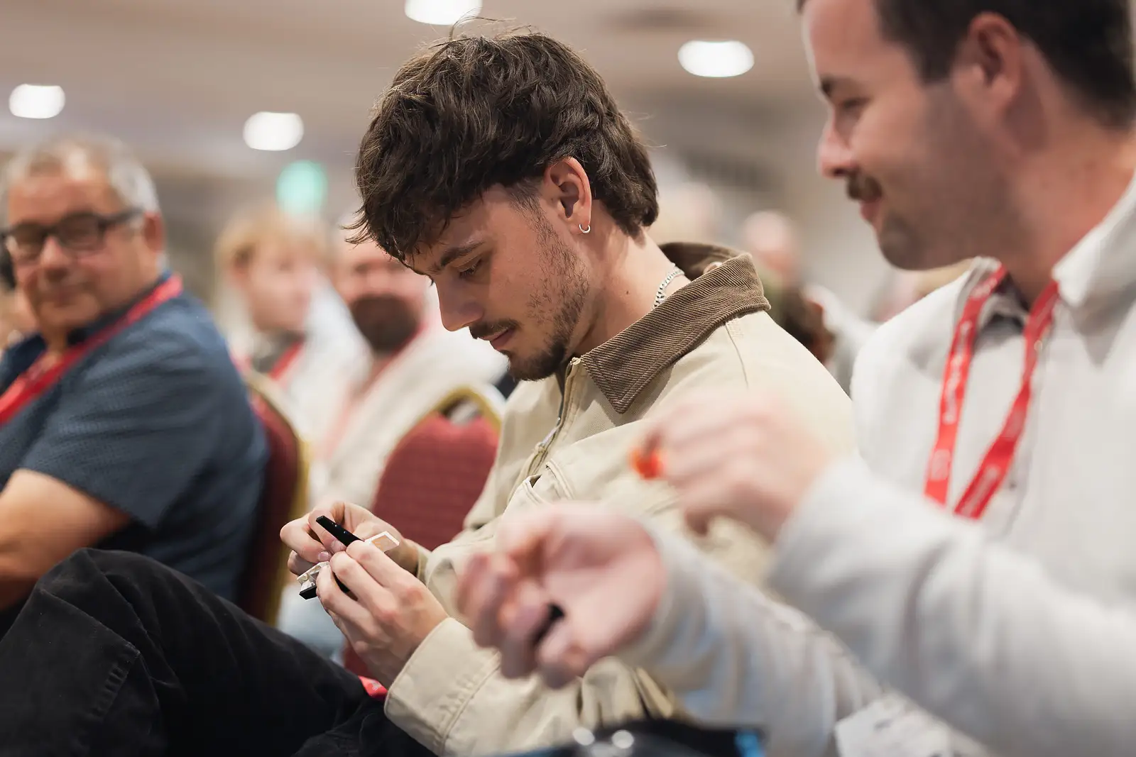 Young male delegate focused on a hands-on activity seated among colleagues at a corporate conference in Somerset