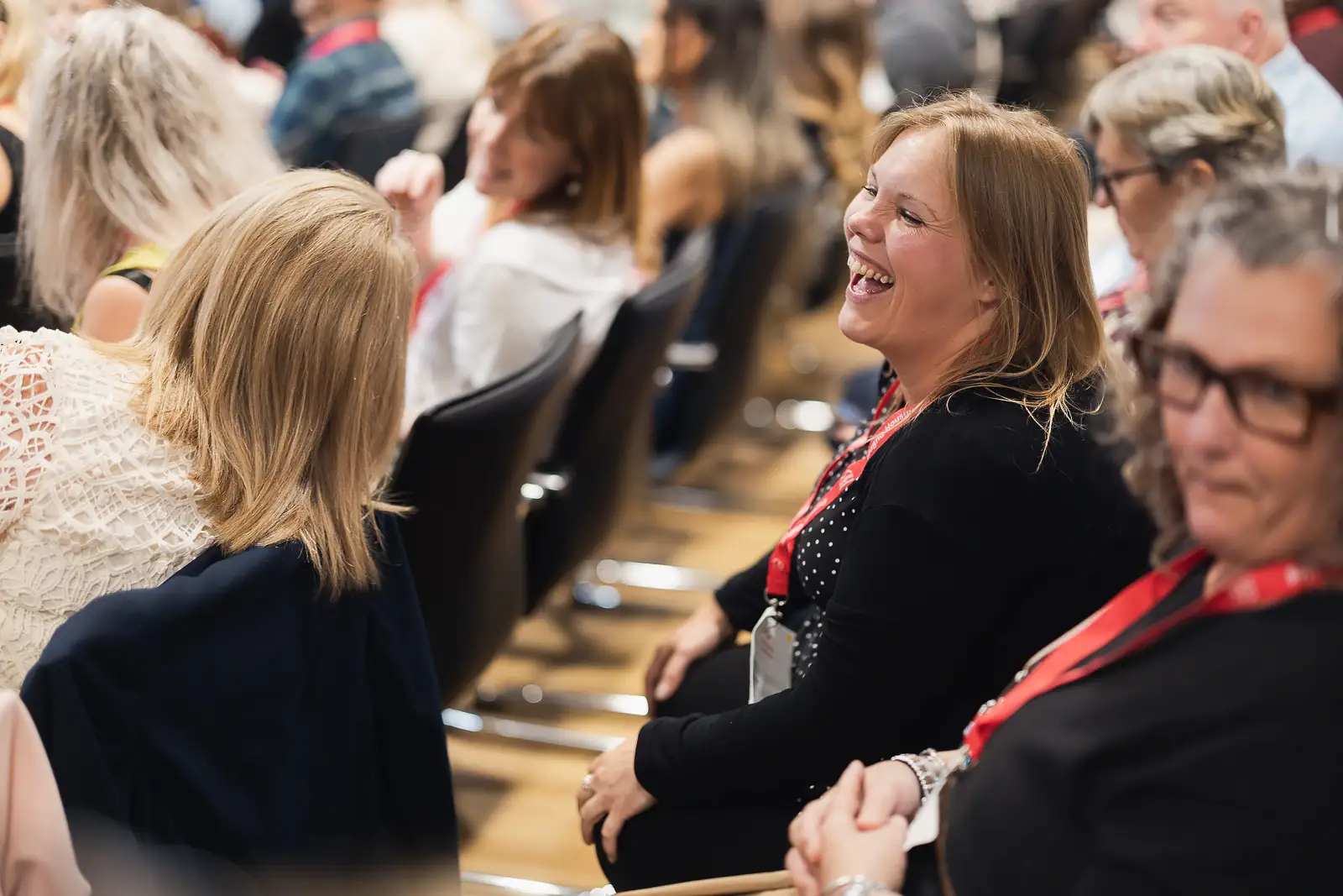 Female delegate laughing warmly while seated in the audience during a corporate event in Somerset