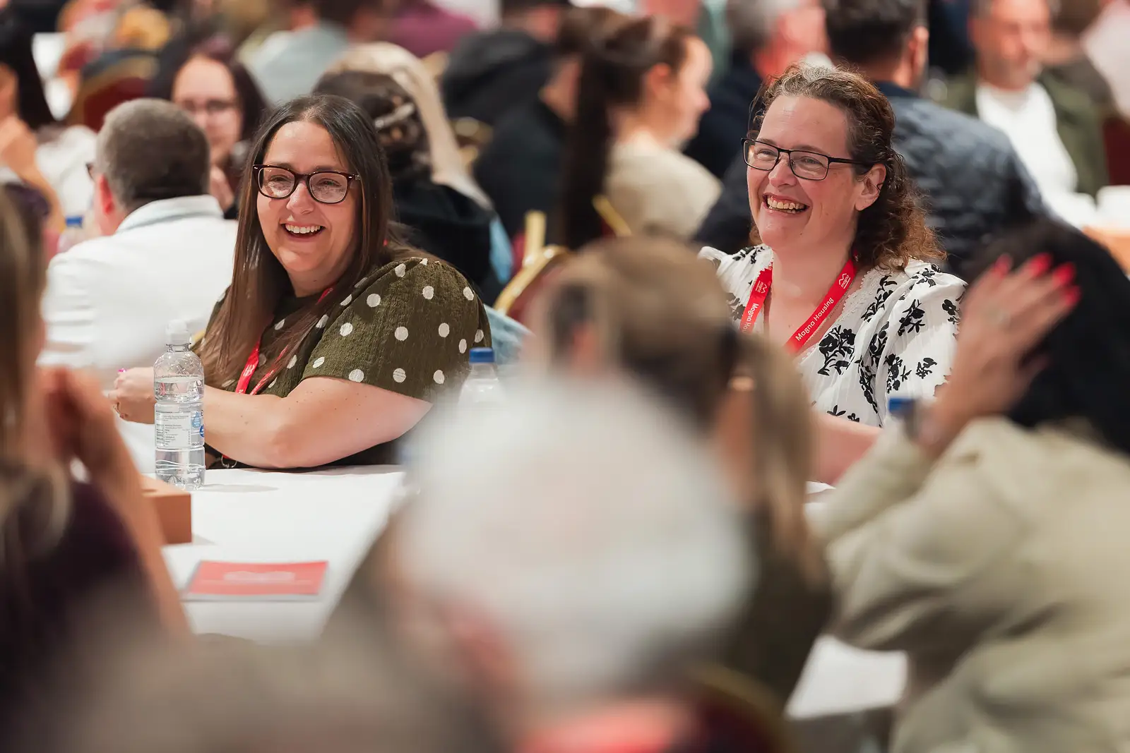 Two delegates laughing during a main stage conference session at a corporate away day in Somerset