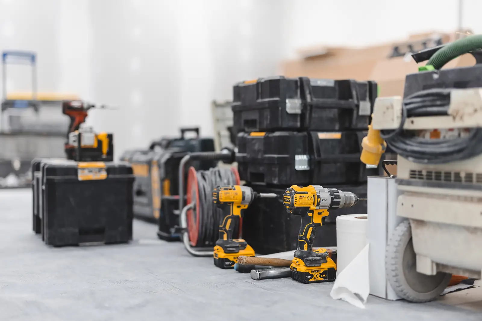 Organised row of DEWALT toolboxes and drills lined up on site floor, shallow depth of field highlighting tool branding