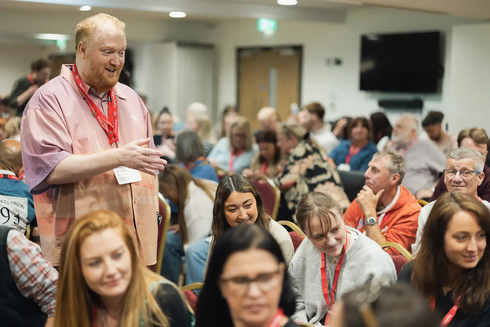 Employee standing and speaking to a large audience of colleagues during an interactive session at a corporate away day at Westlands Theatre