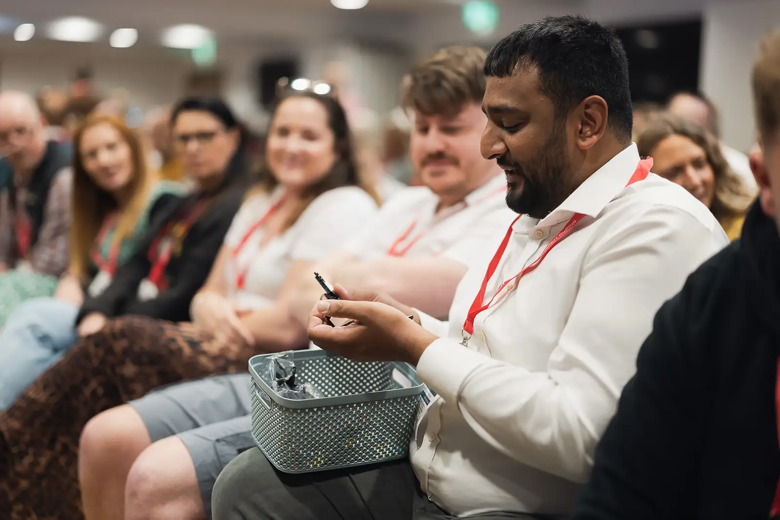 Employee writing a note with colleagues in the background smiling during an interactive session at a corporate conference in Somerset