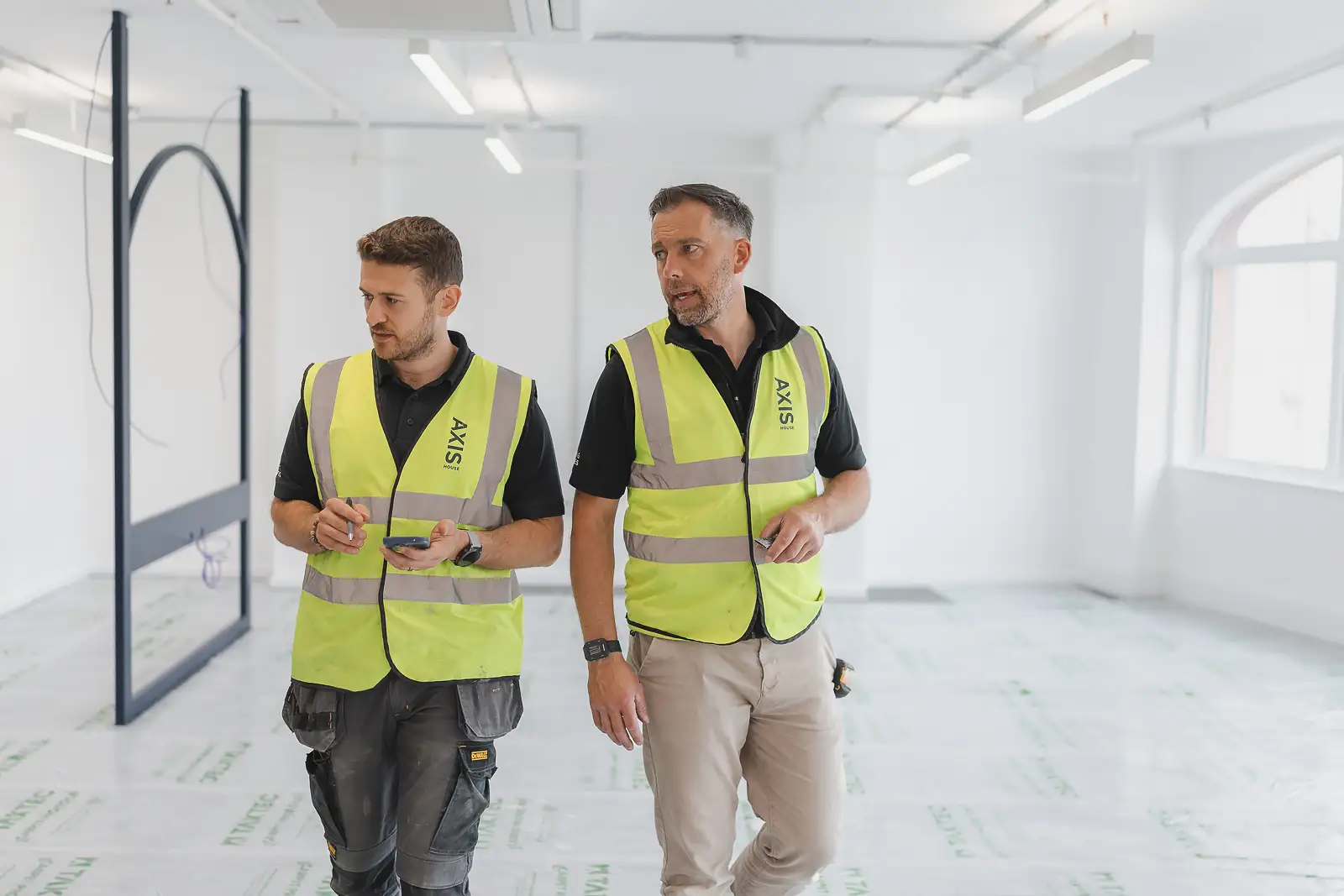 Two site managers in mid-conversation during a walkthrough, captured candidly with natural expression — lifestyle photography on location