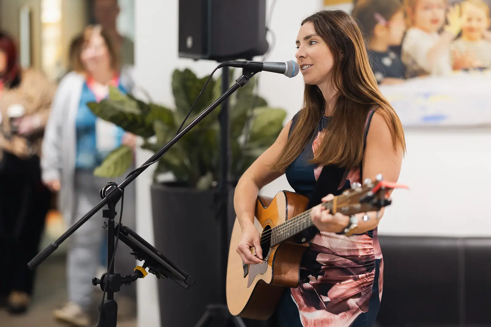 Female musician playing acoustic guitar and singing at a corporate away day event in Somerset