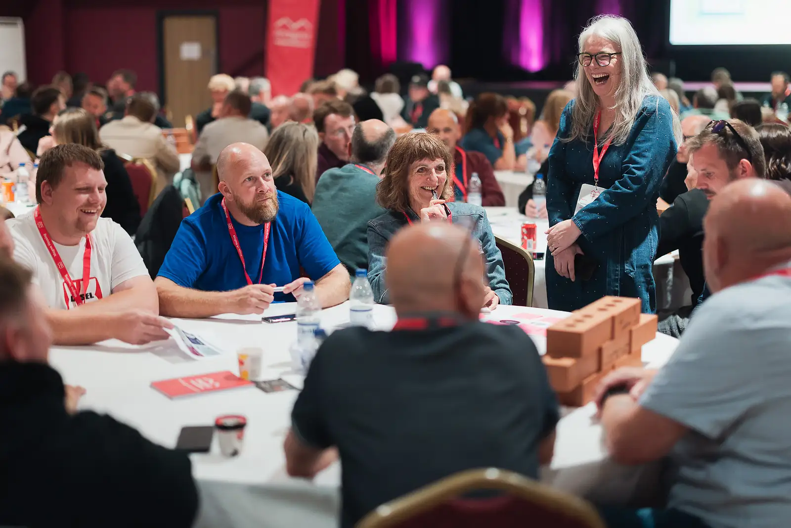Lively group of colleagues laughing and working together at a round table during a corporate conference at Westlands Theatre Somerset