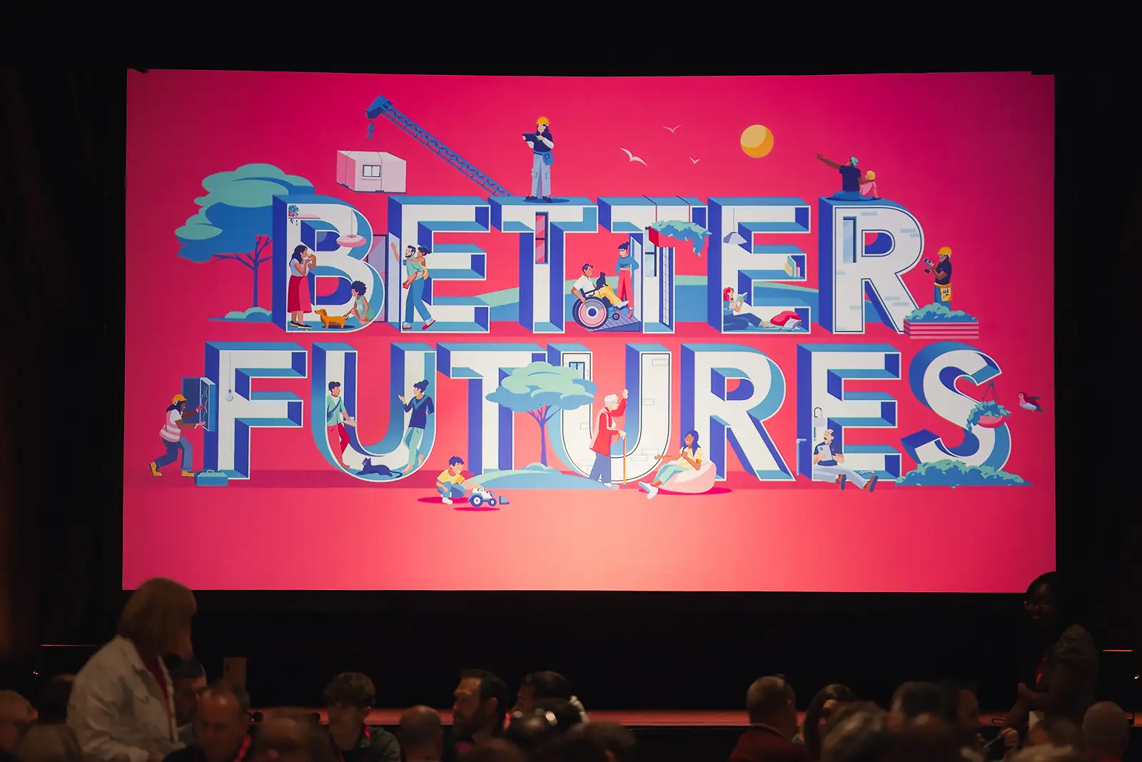 Large projection screen displaying event branding in the main auditorium at Westlands Theatre with delegates seated in the foreground