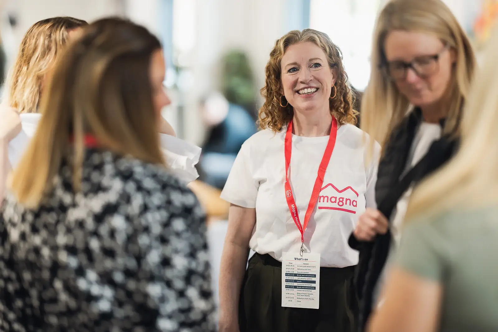 Smiling colleague in branded t-shirt and lanyard during arrival networking at a corporate away day in Somerset