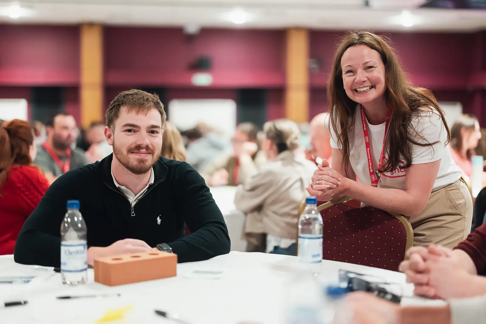 Two colleagues smiling warmly at their table during a workshop session at a corporate away day in Somerset