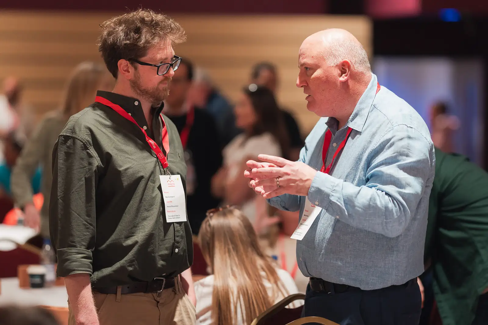 Two male delegates in focused discussion during a break at a corporate conference in Somerset