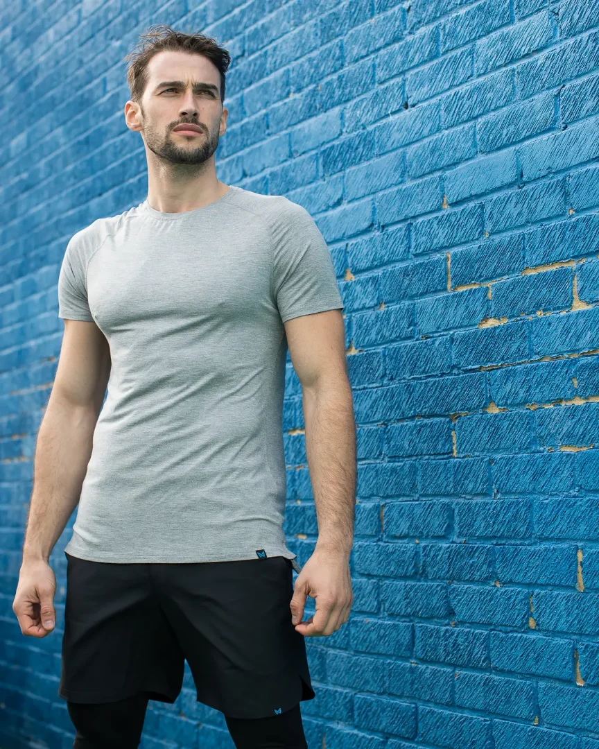 Man in a grey t-shirt against a blue brick wall in Bournemouth, shot for a brand campaign