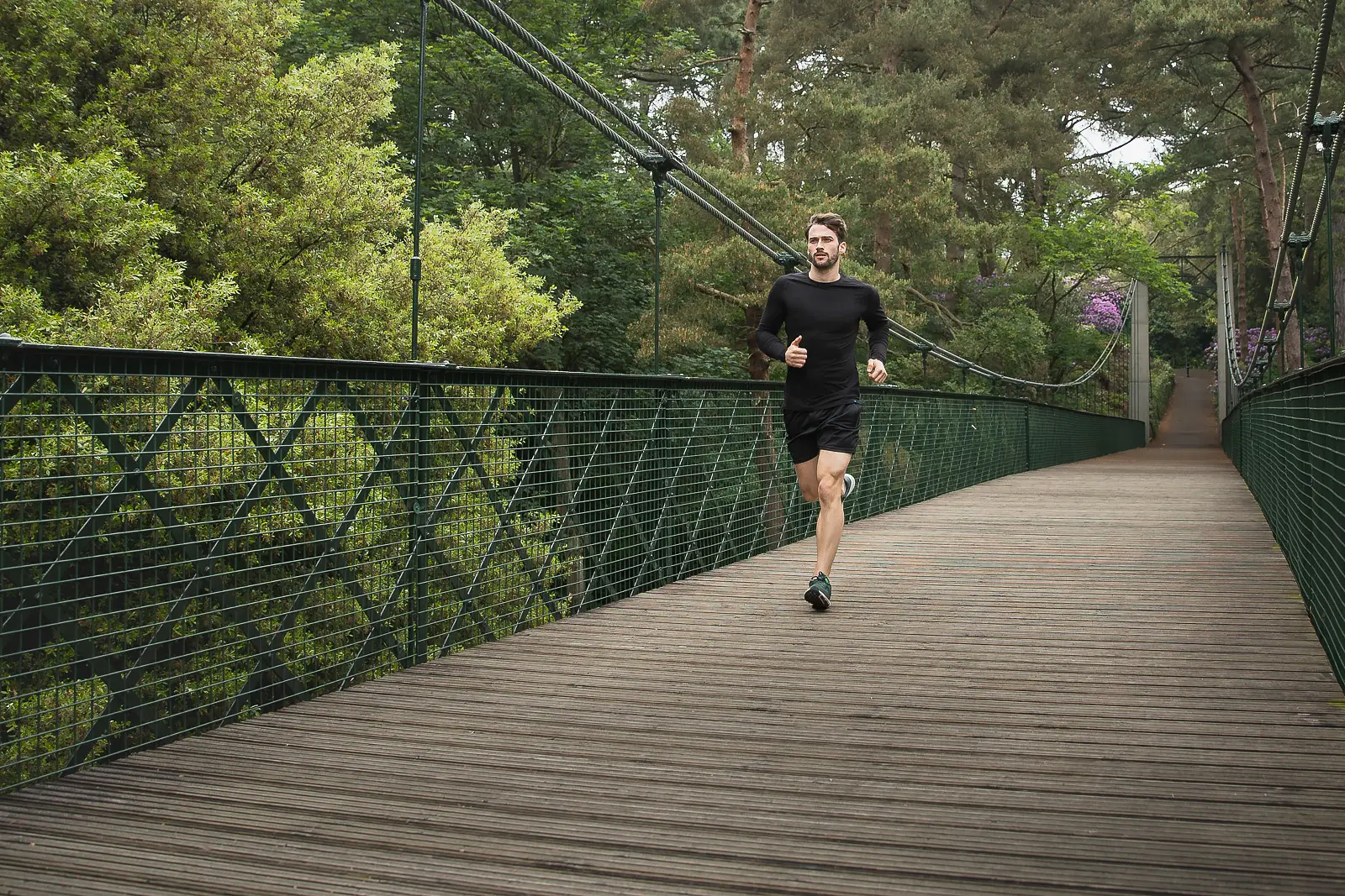 Man running across a wooden suspension bridge in Bournemouth, captured for a campaign photography shoot