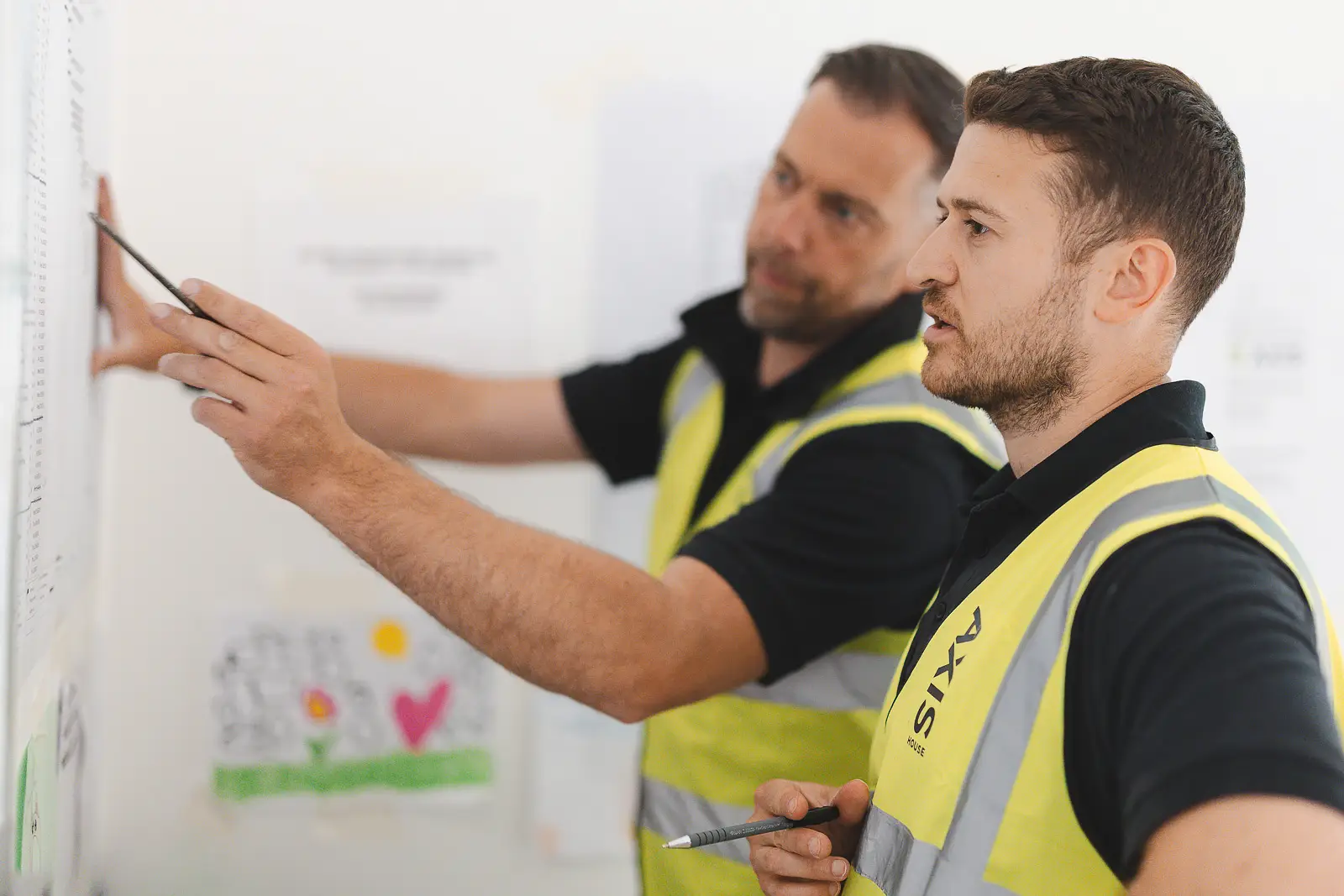 Two men in hi-vis vests reviewing plans on site, from a Bournemouth commercial photography shoot