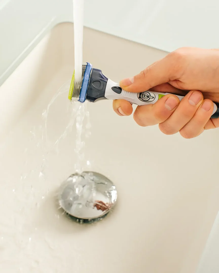 Razor rinsed clean under running water above a sink, part of a Dorset product photography shoot