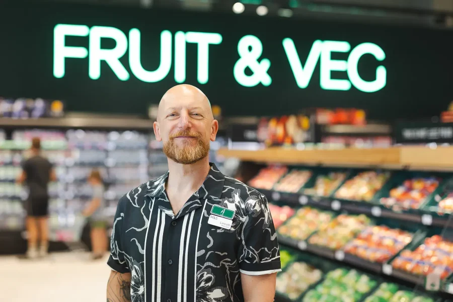 Commercial portrait of the store manager in the Poole food hall, with produce displays and signage behind him.